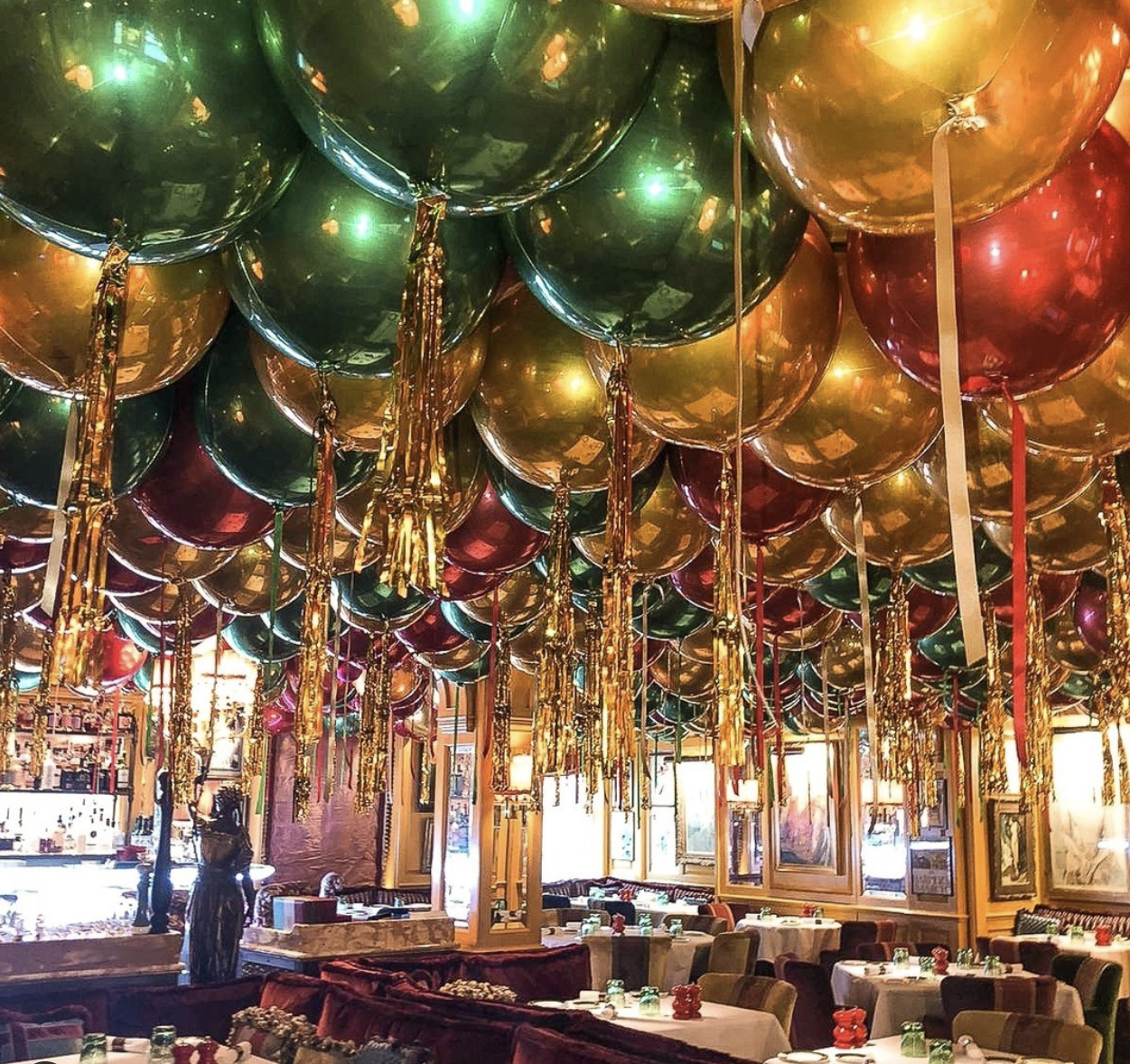 Office Christmas Party Themes, red, gold and green balloons on the ceiling of a venue